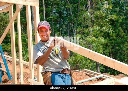 Latin work crew building wooden stick built house home cutting measure nailing on hot day Stock Photo