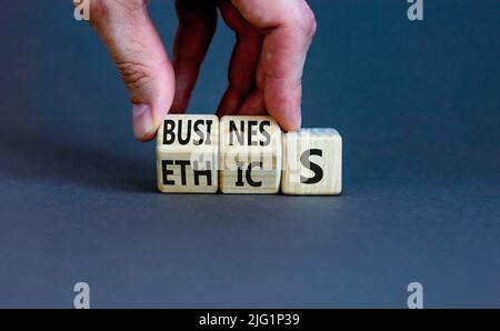Business ethics symbol. Concept words Business ethics on wooden blocks. Businessman hand change words business on ethics. Beautiful grey table grey ba Stock Photo
