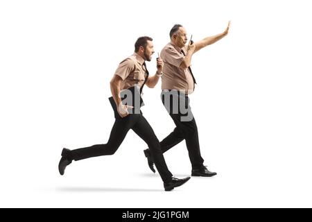 Full length profile shot of two security guards running and using walkie talkie isolated on white background Stock Photo