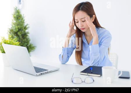 Stressed and headache asian business woman working in office Stock Photo