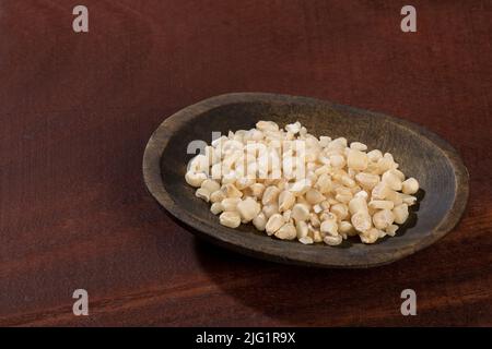Zea mays - Wooden bowl with raw corn kernels, on wooden background. Stock Photo