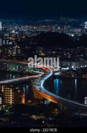 Bird's eye view at night of the illuminated urban expressway circular route crossing in zig-zag the Muromi river passing through the city of Fukuoka t Stock Photo