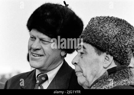 President Ford dons a Russian wool cap upon his arrival in Soviet Union, shown here with Soviet General Secretary Leonid Brezhnev at Vozdvizhenka Airport, Vladivostok, USSR.  November 23, 1974. Stock Photo