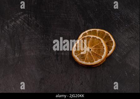 Close-up of two slices of dried orange on a dark metallic background. Copy space. Stock Photo