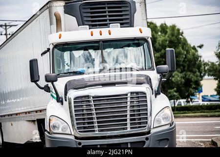 Day cab powerful white big rig industrial semi truck tractor for local freights and delivery transporting frozen commercial cargo in refrigerator semi Stock Photo