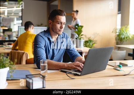 Caucasian young businessman working on laptop in creative office Stock Photo