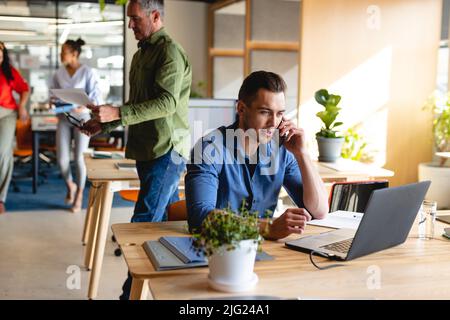 Caucasian young businessman talking on smart phone in creative office Stock Photo