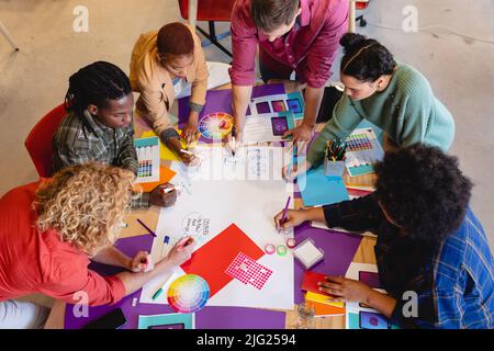 High angle view of multiracial design professionals writing ideas on paper during meeting in office Stock Photo