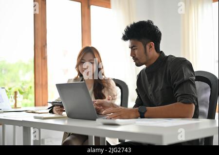 Professional asian male office worker or engineer worker working and discussing with female colleague in the office. Stock Photo