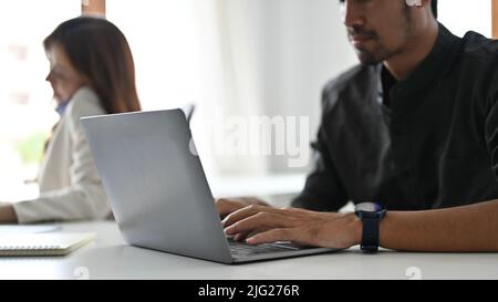 Smart asian businessman or male engineer worker employee using laptop computer, working at his office desk. cropped image Stock Photo