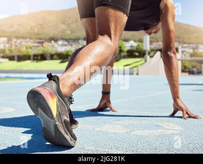 Close up of an athlete getting ready to run track and field with his feet on starting blocks ready to start sprinting. Close up of a man in starting Stock Photo