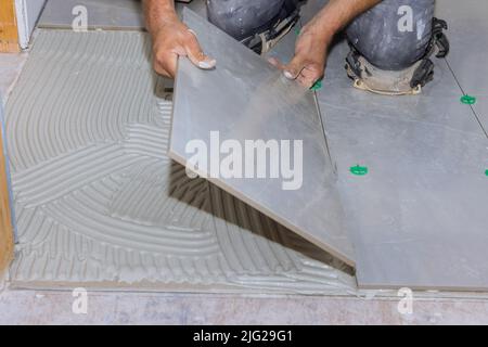 Using adhesive to install ceramic floor tiles in a home construction project Stock Photo