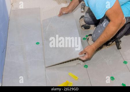 Placing ceramic tiles on glue-smeared floors using tile adhesive Stock Photo