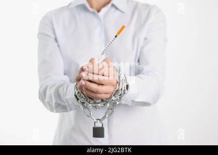 Female hands tied with chain holding insulin syringe Stock Photo