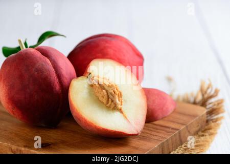Fresh  peaches on wood plate and white background. Peaches are widely eaten fresh and are also baked in pies and cobblers and rich vitamin A. Stock Photo