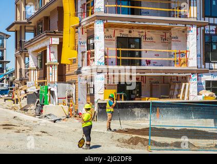 Workers On Constuction Site Working Together Teamwork Concept. People working on new development construction-June 24,2022-Vancouver BC Canada. Street Stock Photo