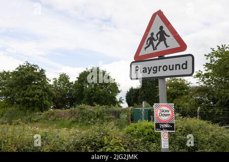 A British road sign signifying children going to or from school or a playground ahead. The sign is fixed to a lamppost Stock Photo