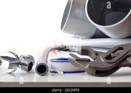 Detail of tools for plumbing repair on white table and white isolated background. Front view. Horizontal composition. Stock Photo