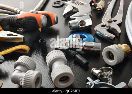 Detail of group of plumbing materials and tools on black table. Elevated view. Horizontal composition. Stock Photo