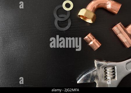 Conceptual background of black wooden desk with plumbing tools for sale. Top view. Horizontal composition. Stock Photo