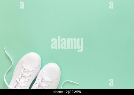 All white sneakers on mint green background. Top view,flat lay Stock Photo