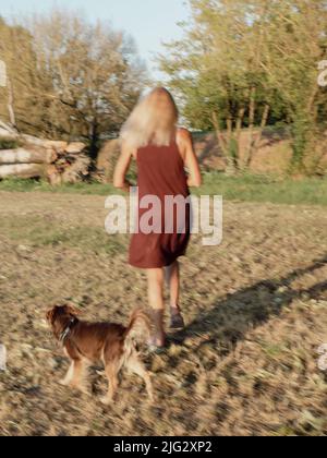 tall fit caucasian adult blonde woman in a park near a big fallen tree. Outdoor portrait of positive confident mature woman. Smiling female blonde in Stock Photo