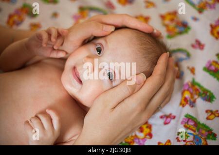 Mother holding head of her newborn daugther in hands Stock Photo