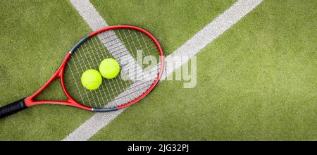 tennis balls and racket on green synthetic grass court background. top view with copy space Stock Photo