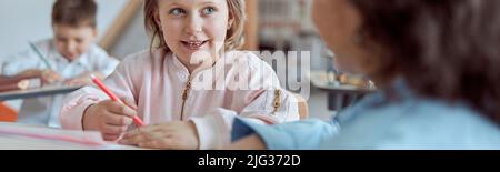 Happy kind teacher is helping kids in elementary school lessons Stock Photo