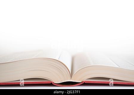 Open book with red cover on white background. Narrow depth of field Stock Photo
