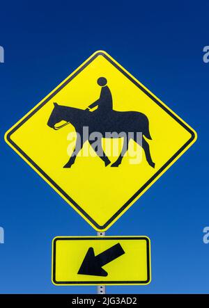 Yellow horse crossing sign against blue sky Stock Photo