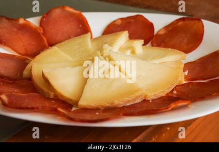 Manchego cheese on a bed of Lomo, dry cured sausage. Stock Photo