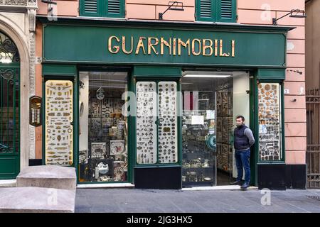 Furniture fittings shop exterior with the seller standing at the entrance in Via San Lorenzo, one of the main street of Genoa, Liguria, Italy Stock Photo