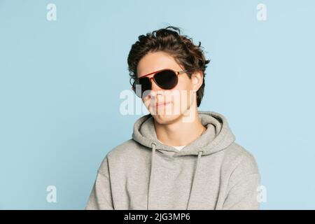 Half-length portrait of stylish young boy, teen in casual style clothes posing isolated over grey background. Back to school, emotions, youth, fashion Stock Photo