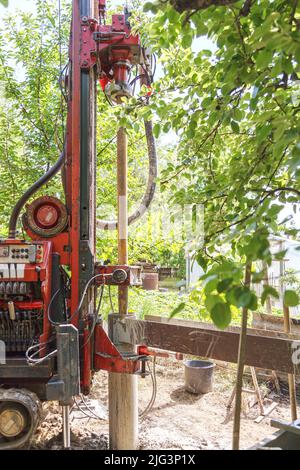 Photo of a drilling rig with a pipe for drinking water drilling against the background of trees warm sunny day. Stock Photo