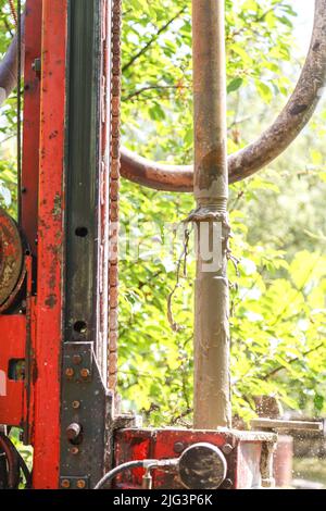 Photo of a drilling rig with a pipe for drinking water drilling against the background of trees warm sunny day. Stock Photo