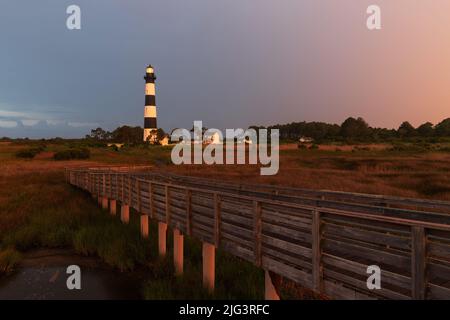Boardwalk over saltwater march leading to Bodie Island lighthouse under stormy skies in Nags Head, North Carolina, Outer Banks Stock Photo