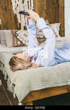 The girl holds the phone on outstretched arms.  Stock Photo