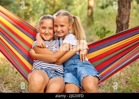 Kids relax in colorful rainbow hammock. cation. Children relaxing. Stock Photo