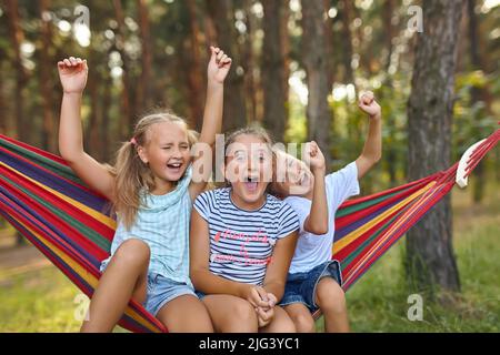 Fun in the garden kids playing in colorful hammock Stock Photo