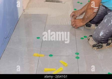 Working on the tile leveling system in the bathroom with plastic clips and wedges Stock Photo