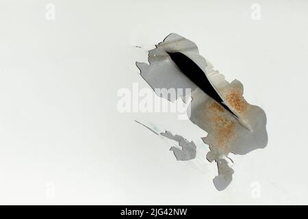 Hole in metal. Damaged steel with white paint. Broken surface of car. Damage to vehicles. Stock Photo