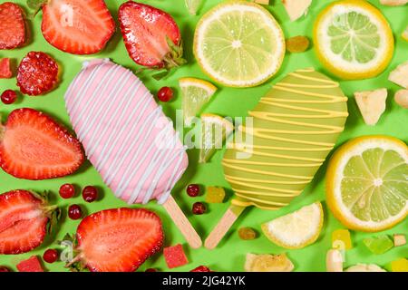 Two ice creams on a sticks - strawberry and lemon on a green background. Summer fruit desserts. Stock Photo