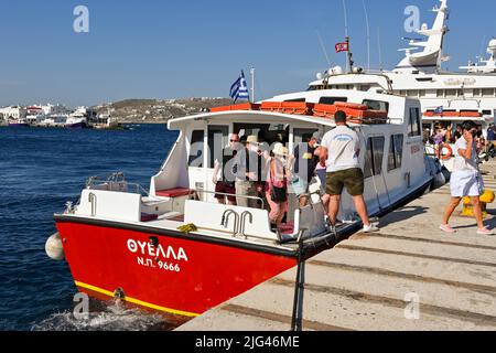 Mykonos, Greece - June 2022: Passengers from a cruise ship getting off a small boat after arriving in the harbour of the Greek Island of Mykonos Stock Photo