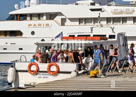 Mykonos, Greece - June 2022: Passengers from a cruise ship getting off a small boat after arriving in the harbour of the Greek Island of Mykonos Stock Photo