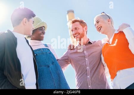 Group of four young diverse friends having fun and smiling outdoors. Stock Photo