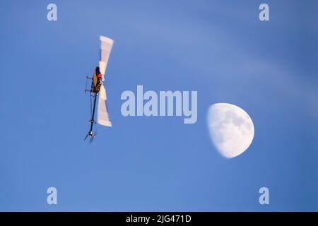 Radio controlled model helicopter doing air acrobatics at sunset Stock Photo