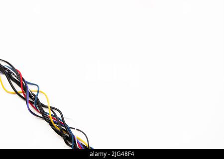 Many colorful electrical cord cables twist together into single frame line on white background. Top view, copy space Stock Photo