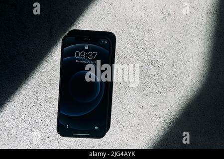 Kaliningrad, Russia - April 15, 2021: Black Apple iPhone 12 on a gray background. Latest model phone. Stock Photo