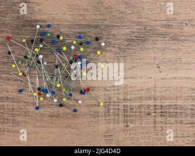 Colored straight pins on wooden table, copy space. Ball-point pins used to fasten pieces of cloth or paper together. Tool to the sewist Stock Photo